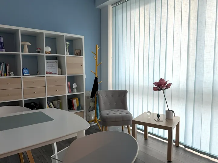 Poltroncina grigia e tavolino accanto alla vetrata nello studio di psicologia a Roma Eur