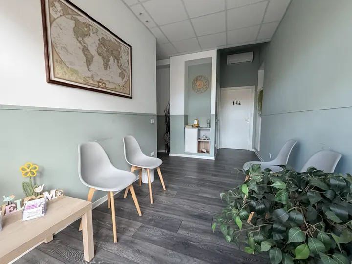 Sala d'attesa dello studio, con sedute chiare e pareti verde salvia